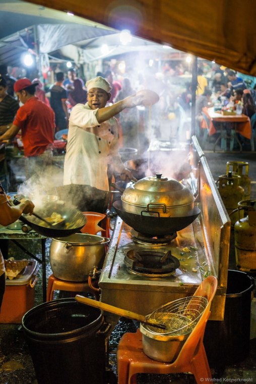 A chef pouring a mixture into a pot in Kota Kinabalu, Malaysia.